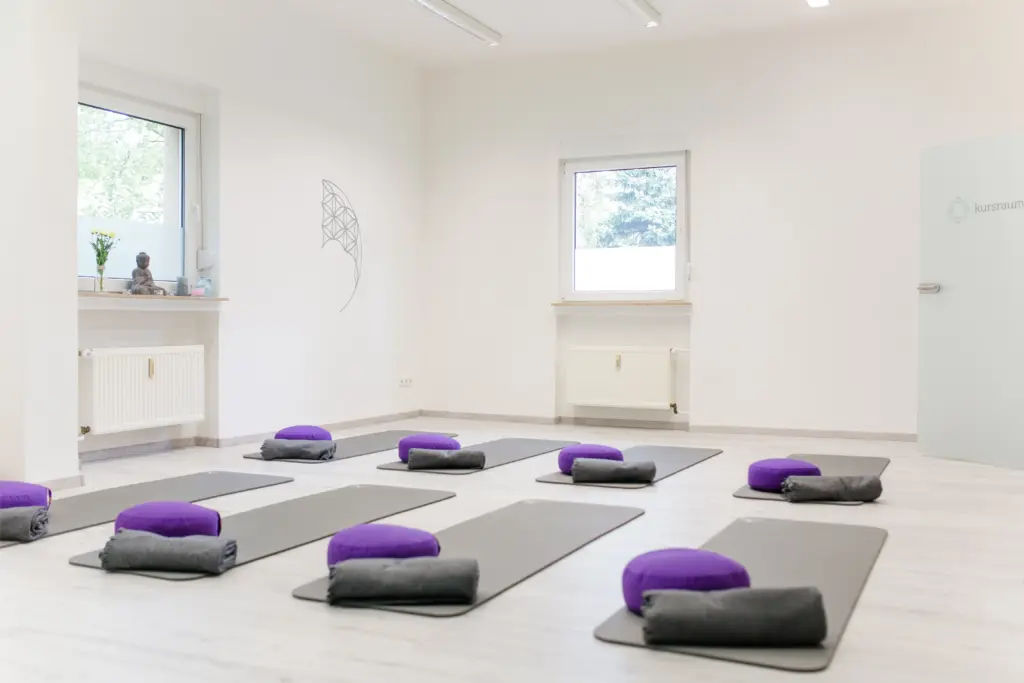 Heller Kursraum mit ausgelegten Yogamatten, Meditationskissen und der Blume des Lebens an der Wand, bodymind in Mülheim an der Ruhr